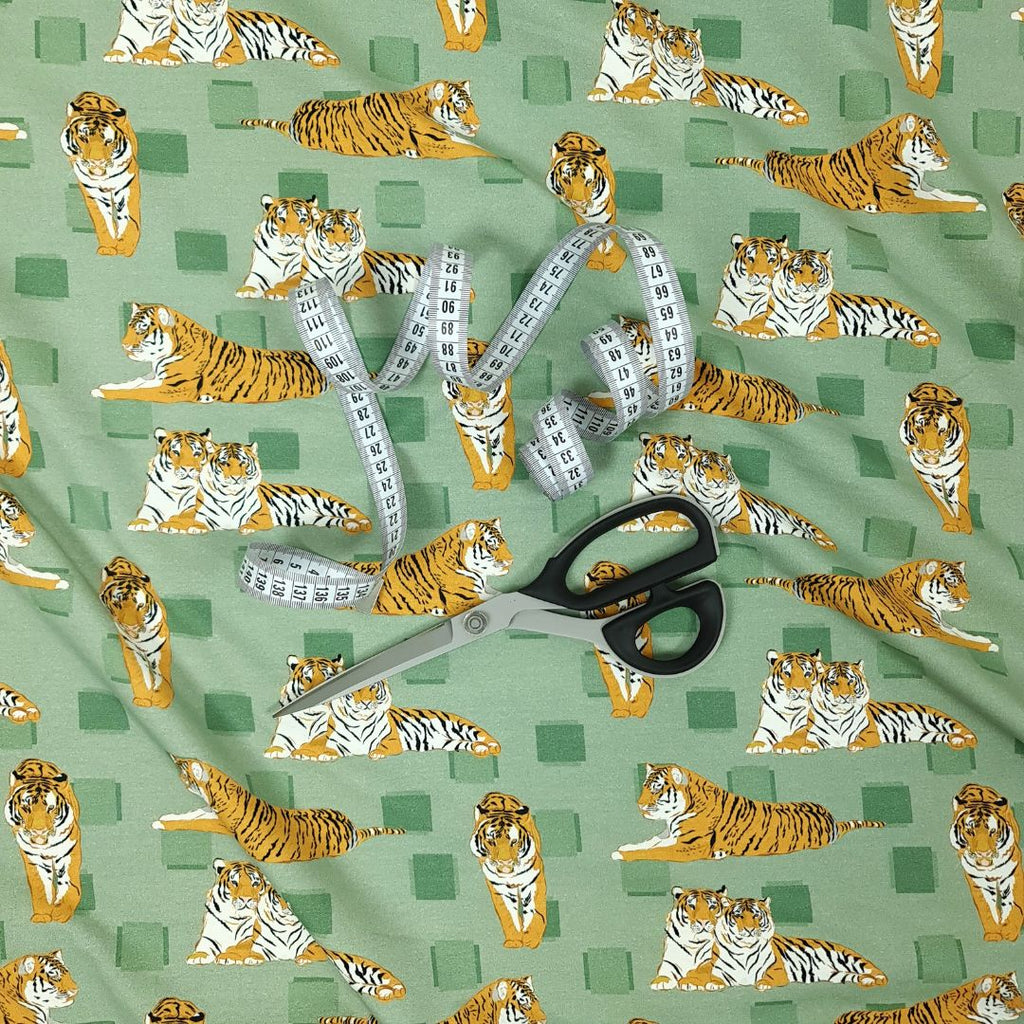Det här single jersey trikå-tyget har ett mönster med tigrar på en mjuk grön bakgrund. Tyget er gjort av 95 % ekologisk bomull, 5 % elastan och känns mjukt och har en trevlig stretch vilket gör det perfekt för att sy bekväma barnkläder.